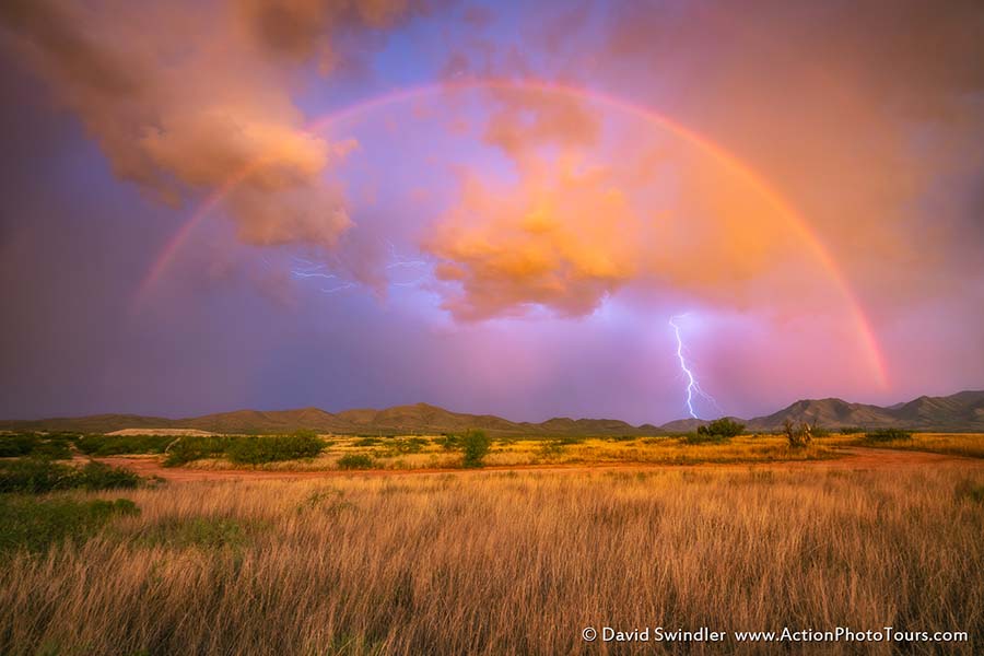 Beauty and the Beast We have been having a blast on our Storm Chasing Workshops, especially with all the active monsoon activity over the past few days! Here is a shot from our chase last night. As sunset approached, a large rainbow appeared. But right as we started to photograph it, the rain began to fall in earnest. We quickly drove further away to escape the rain and got there just in time to catch the last of the giant rainbow. The wind was blowing and raindrops were quickly collecting on my lens. I hooked up my lightning trigger and this shot was captured right in-between when I was blowing off my lens! About 2 mins later, we were all running for cover as the rain started to pour down. Dramatic lightning shows continued all around us for several more hours. What a fun night we had!!