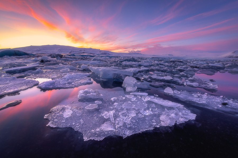 What a great way to finish the day with our Iceland Workshop! As we got closer to sunset, we saw the clouds were going to be better back behind us. So we loaded everyone up and rushed over to this spot just in the nick of time. Even though the water was quite calm, the icebergs still move around. I took a number of shots at higher ISO to help freeze the motion, but I didn't like seeing the mild ripples on the water. So I took a few shots at ISO 100 and was able to get one where most everything held still. This is a single exposure at 14mm. A good foreground needs to be prominent and clean. This particular iceberg was perfect as it didn't have a bunch of competing ice chunks nearby. Even though our 2021 Iceland Winter Workshop sold out last week, make sure you join our email list for upcoming 2021 Workshop Opportunities!  Join Here:  http://eepurl.com/1Nya1